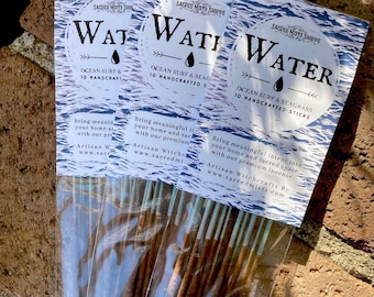 May include: A package of 10 handcrafted incense sticks with a blue and white label that reads "Water Ocean Surf & Seagrass". The label also includes the text "Sacred Mists Shoppe" and "Artisan Witchcrafts By www.sacredmists.com".