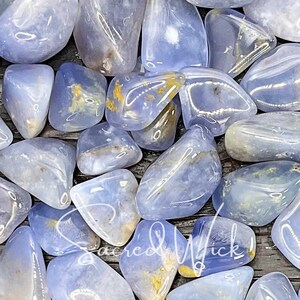 A macro close-up of tumbled blue chalcedony in bright lighting, showcasing its soft, soothing blue tones and gentle energy known for promoting calm, emotional balance, clear communication, and spiritual connection.