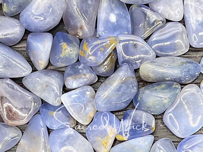 A macro close-up of tumbled blue chalcedony in bright lighting, showcasing its soft, soothing blue tones and gentle energy known for promoting calm, emotional balance, clear communication, and spiritual connection.