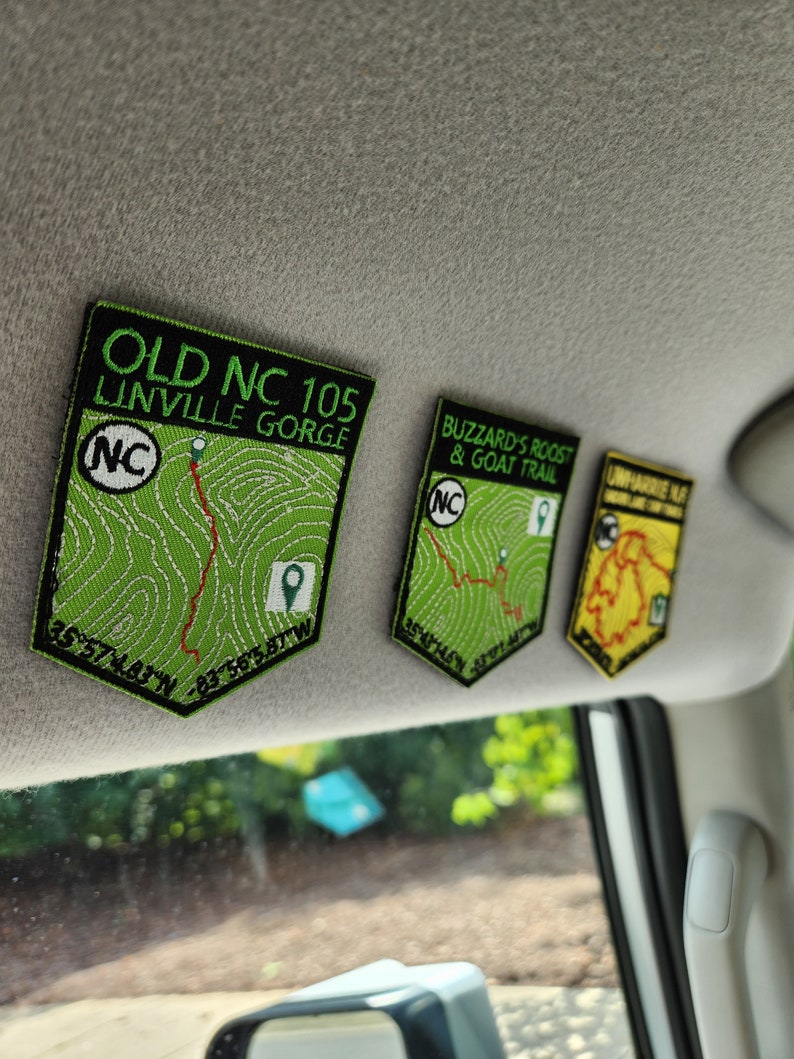 May include: Three green and black embroidered patches with the text "Old NC 105 Linville Gorge", "Buzzard's Roost & Goat Trail", and "Uwharrie Nat'l Forest" with a map of each location and coordinates.