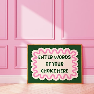 May include: A framed art print with the text "ENTER WORDS OF YOUR CHOICE HERE" in green and pink. The text is centered on a cream-coloured background, framed by a wavy pink border, set against a dark green backdrop. The frame is gold.