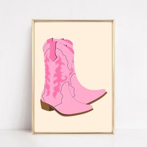 May include: A pair of pink cowboy boots with intricate floral embroidery. The boots are set against a light beige background.
