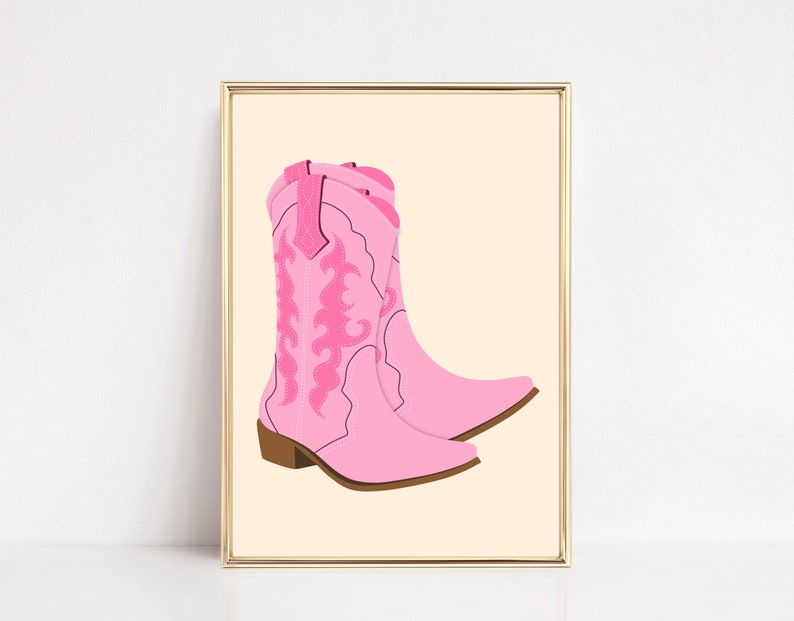May include: A pair of pink cowboy boots with intricate floral embroidery. The boots are set against a light beige background.