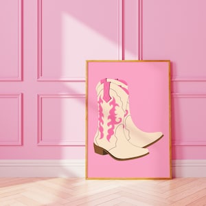 May include: A framed illustration of a pair of white cowboy boots with pink embroidery on a pink background.