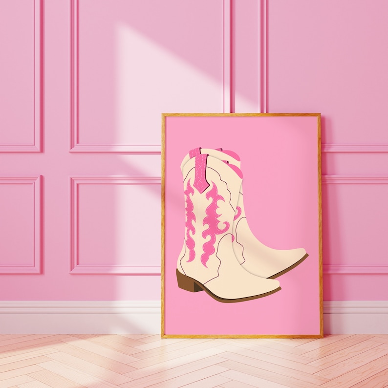 May include: A framed illustration of a pair of white cowboy boots with pink embroidery on a pink background.