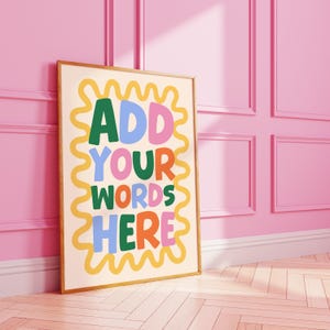 May include: A framed poster with the text "ADD YOUR WORDS HERE" in colorful, playful lettering. The poster has a cream-colored background with a yellow wavy border. The text is in green, blue, pink, and orange.