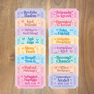 May include: A collection of colorful ticket-style cards with various romance novel themes, including "Reverse Harem," "Friends to Lovers," and "Arranged Marriage." Each card features decorative elements and the words "Book Club" and "Lifetime Membership."