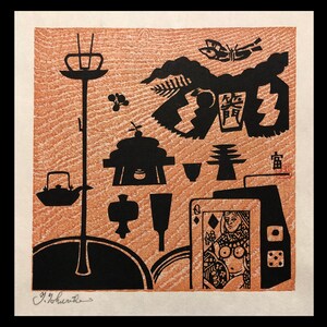 May include: A black and white woodblock print of a Japanese scene with a woman holding a playing card, a tea set, and a pagoda. The print is on a brown background with the artist's signature in the bottom left corner.