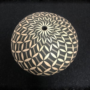 Könnte beinhalten: Ein schwarzer und weißer Keramiktopf mit geometrischem Muster. Der Topf ist rund und hat ein kleines Loch in der Mitte.