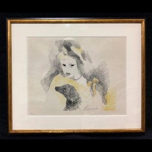 Può includere: Un disegno in bianco e nero di una donna con un cane. La donna indossa un vestito giallo e una fascia bianca per capelli. Il cane è seduto sulle sue ginocchia. Il disegno è firmato "Laurencin" in basso a destra.