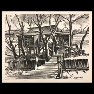 May include: A black and white print of a stilt house on a riverbank, with a wooden walkway leading to the entrance. Bare trees frame the house, and a steamboat is visible in the distance. The print is signed by Arthur Covey.