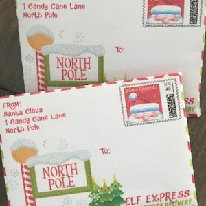 Puede incluir: Dos sobres blancos con ribetes rojos y verdes. Los sobres están dirigidos a Santa Claus en 1 Candy Cane Lane, Polo Norte. Los sobres tienen un letrero rojo y verde de Polo Norte con un muñeco de nieve en la parte superior. Los sobres tienen un sello con un dibujo animado de Papá Noel. El sobre de abajo tiene las palabras "ELF EXPRESS ENTREGA MUNDIAL" impresas en él.