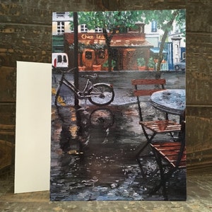 May include: A painting of a Parisian street scene with a bicycle parked in front of a cafe. The cafe has a sign that reads "Chez Leo". The scene is set on a rainy day, and the ground is wet and reflective. There is a table and chairs outside the cafe, and the table is wet from the rain.