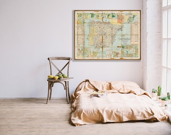 Puede incluir: Un mapa antiguo enmarcado de España cuelga sobre una cama con ropa de cama beige. Una silla de madera con una pequeña mesa sostiene cuencos amarillos y fruta verde. La habitación tiene una paleta de colores neutros.