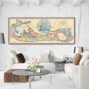 May include: A framed vintage map of Bermuda, featuring a detailed cartographic illustration with a central circular emblem of a ship. The map is in a dark brown frame, hanging above a white sofa in a modern living room.