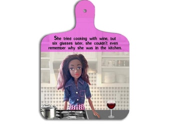 May include: A pink cutting board with a humorous quote about cooking with wine. The quote reads: "She tried cooking with wine, but six glasses later, she couldn't even remember why she was in the kitchen."