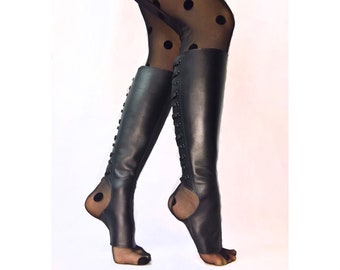 May include: Black leather knee-high boots with laces up the back. The boots have an open toe design and are made of a soft, supple leather.