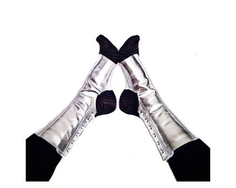 Peut inclure: Une paire de chauffe-jambes en cuir argenté avec des chaussettes noires en dessous. Les chauffe-jambes ont un design à lacets.