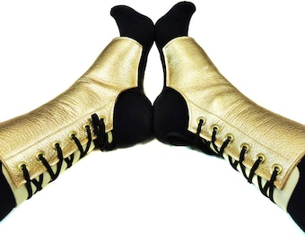 May include: A pair of gold leather leg warmers with black laces. The leg warmers are worn over black tights.
