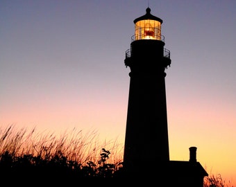 May include: A silhouette of a lighthouse with a lit window against a pink and purple sunset sky.