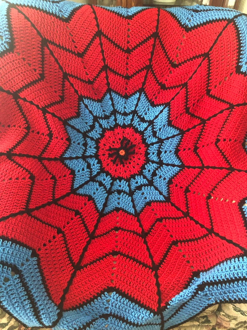May include: A crocheted blanket with a red, blue, and black spiderweb design.