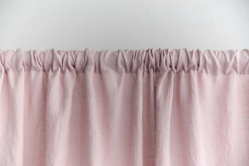 Puede incluir: Primer plano de una cortina de lino rosa con la parte superior fruncida. La cortina est&aacute; hecha de una tela suave y natural y tiene un aspecto relajado y casual.