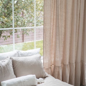 Puede incluir: Una cama con ropa de cama de lino blanco y beige, incluyendo una almohada de apoyo con iniciales bordadas. La cama est&aacute; situada cerca de una ventana con vistas a &aacute;rboles verdes y una valla marr&oacute;n.