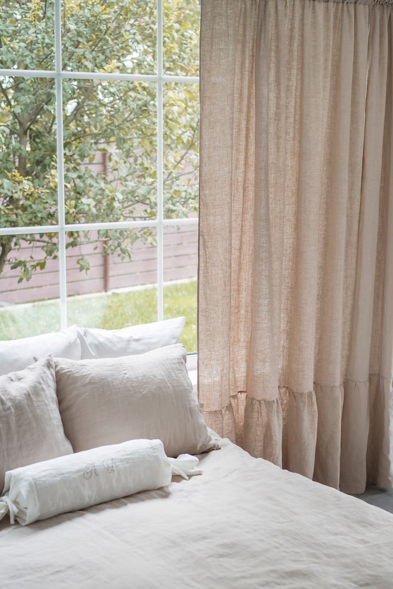 Puede incluir: Una cama con ropa de cama de lino blanco y beige, incluyendo una almohada de apoyo con iniciales bordadas. La cama est&aacute; situada cerca de una ventana con vistas a &aacute;rboles verdes y una valla marr&oacute;n.