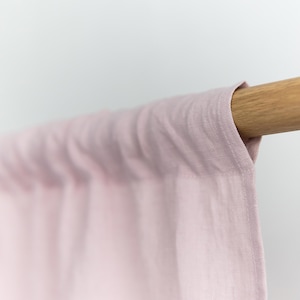 Puede incluir: Una cortina de lino rosa p&aacute;lido colgando de una barra de madera.