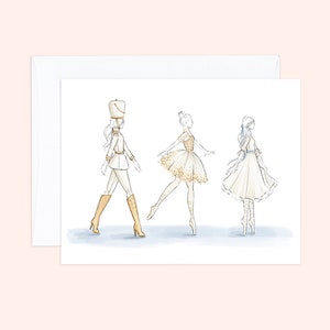 May include: Watercolor illustration of three figures on a white card with an envelope. The figures include a marching band member in a white uniform and gold boots, and two ballerinas in white and gold dresses. The background is a light blue wash.