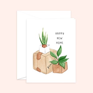 Peut inclure: Une carte blanche avec le texte "Happy New Home" et une illustration aquarelle de deux plantes en pot dans des bo&icirc;tes en carton. Une bo&icirc;te porte l'inscription "Fragile".