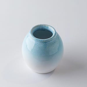 Può includere: Una tazza di ceramica bianca con manico nero e la scritta "But First, Coffee" in nero, con un carattere a mano. La tazza è su una superficie bianca.