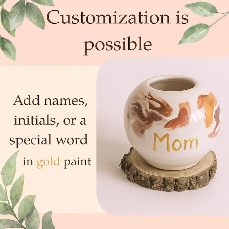 May include: A white ceramic vase with brown and gold abstract designs and the word "Mom" in gold paint. The vase sits on a small wooden slice. Text on the left says "Customisation is possible" and "Add names, initials, or a special word in gold paint."