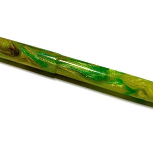 Puede incluir: Una pluma estilogr&aacute;fica verde y dorada con un dise&ntilde;o de m&aacute;rmol. La pluma est&aacute; hecha de resina y tiene un acabado brillante.