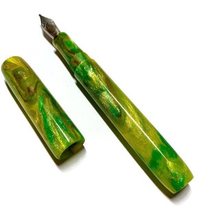 Puede incluir: Una pluma estilogr&aacute;fica verde y dorada con un dise&ntilde;o de m&aacute;rmol. La pluma est&aacute; tapada y la tapa est&aacute; a un lado.