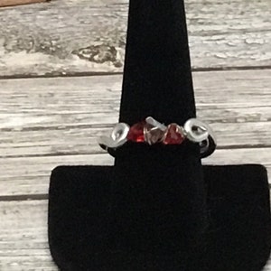 May include: A silver ring with red and clear glass stones set in a wavy design.