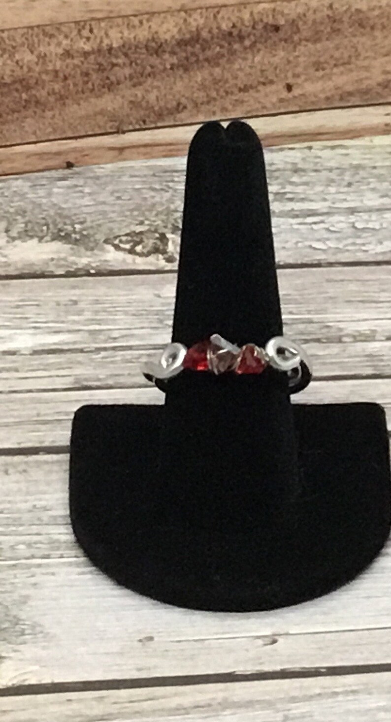 May include: A silver ring with red and clear glass stones set in a wavy design.