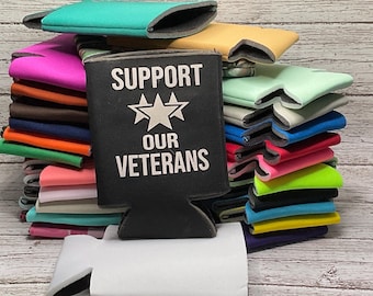 May include: A stack of colorful neoprene can coolers, with a black cooler in the front that says "Support Our Veterans" in white lettering. The black cooler has three white stars.