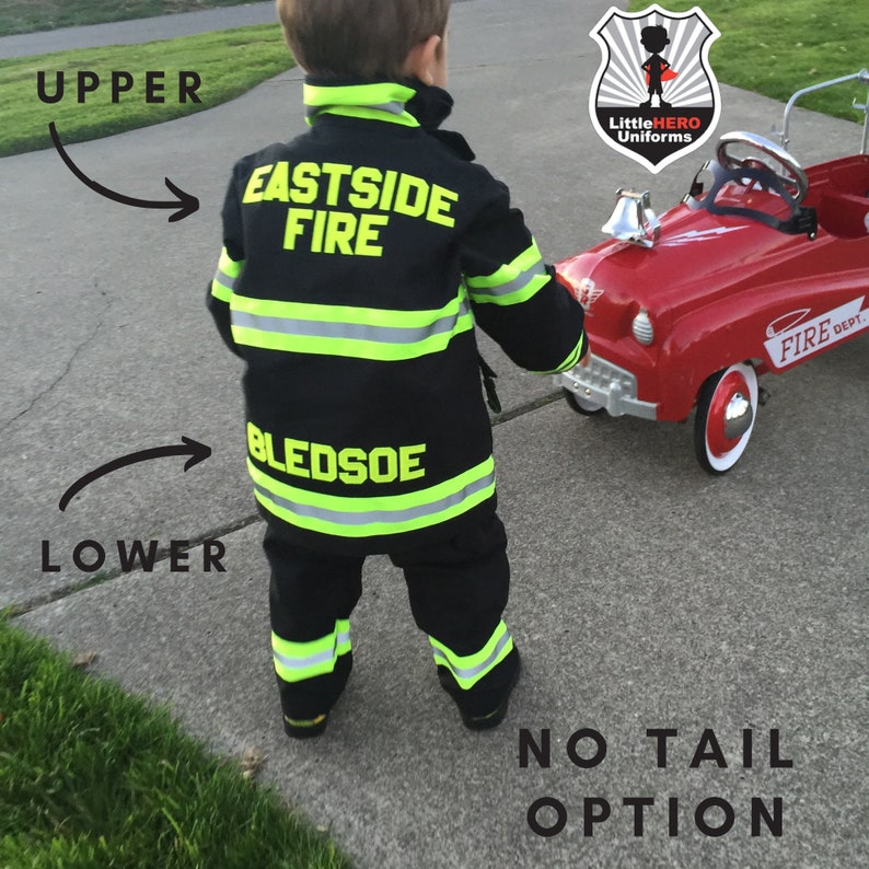 May include: A child wearing a black firefighter costume with yellow reflective stripes. The costume has the words "Eastside Fire" and "Bledsoe" on it. The child is pulling a red toy fire truck with a white steering wheel and a bell.