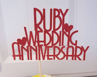 May include: Red glitter cake topper with the words "Ruby Wedding Anniversary" and two small hearts.