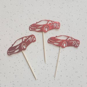 Könnte beinhalten: Drei rote Glitzer-Auto-Cupcake-Topper. Jeder Topper zeigt eine rote Glitzer-Autosilhouette auf einem Holzstiel.