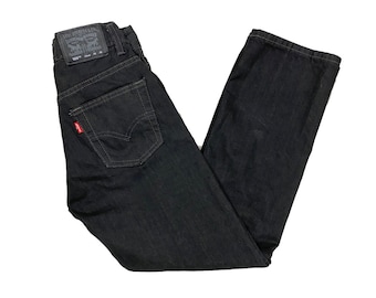 Puede incluir: Vaqueros de mezclilla negros con un parche rojo de Levi's en el bolsillo trasero. Los vaqueros tienen un corte recto.