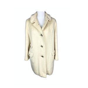 May include: A cream-colored wool coat with a collar, four buttons, and two flap pockets.
