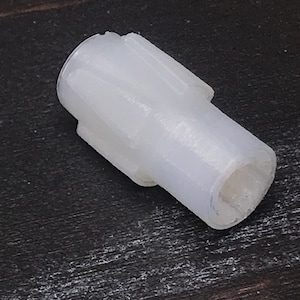 Puede incluir: Engranaje de plástico blanco con un cuerpo cilíndrico liso y una cabeza en forma de estrella.