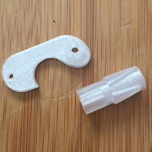 May include: Two white plastic pieces, one is a gear and the other is a C-shaped piece with a hole in the centre.