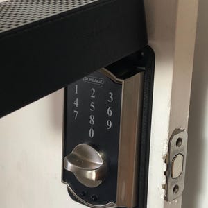 May include: A silver Schlage keypad door lock with a black keypad and a black cover. The keypad has numbers 1 through 9 and 0. The lock is mounted on a white door.