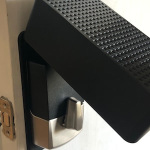 May include: A black door lock with a silver handle and a black cover with a textured surface.