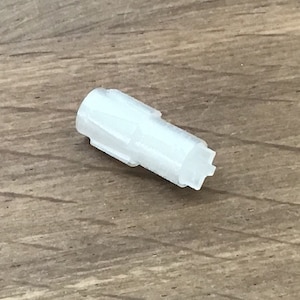 Może przedstawiać: Biały plastikowy ząbkowany element z gwiazdką na końcu.