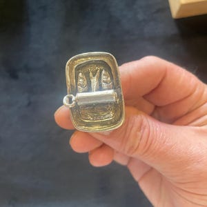Puede incluir: Encanto de plata en forma de lata de sardinas con tres sardinas dentro. El encanto tiene un anillo unido a la parte superior.