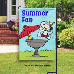 May include: A garden flag with the words "Summer Fun" in blue. The flag features a cartoon of Snoopy wearing a snorkel and Woody under a red umbrella. The flag is displayed on a black metal stand.
